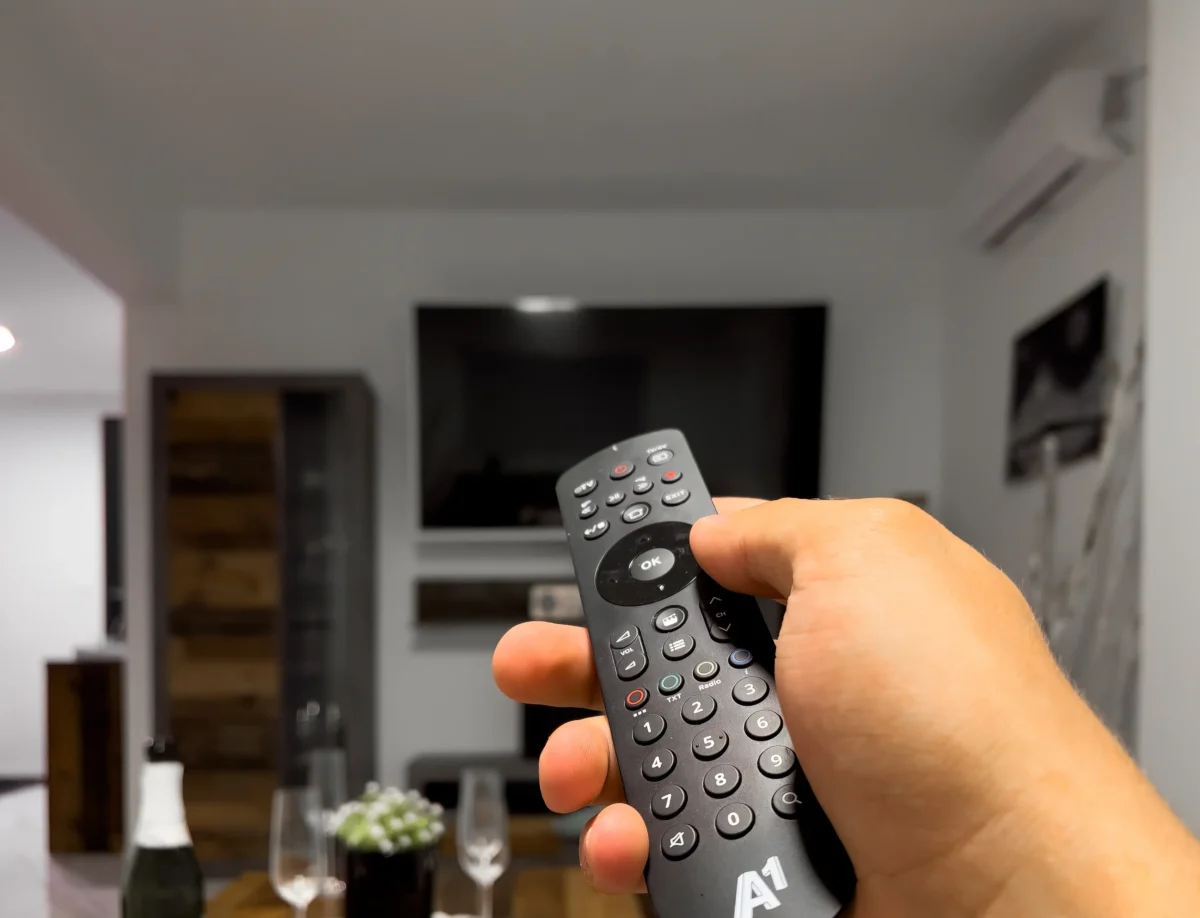 Člověk míří ovladačem na TV.