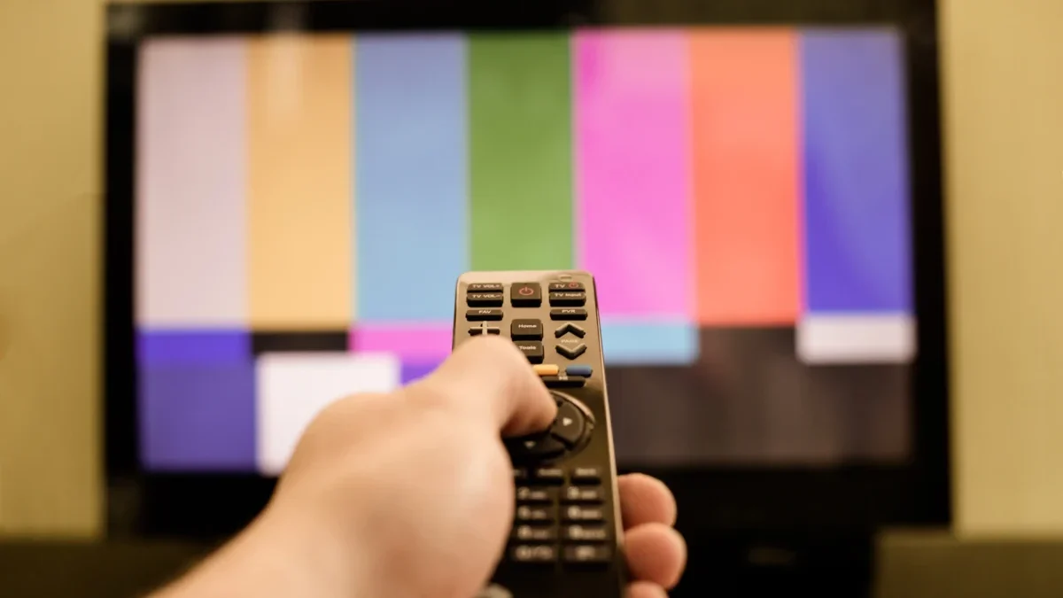 Člověk míří ovladačem na TV.