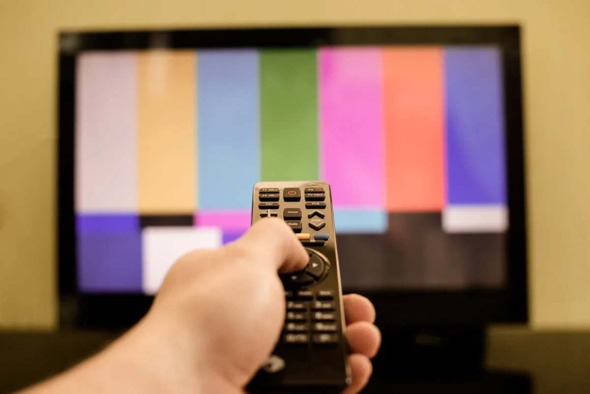 Člověk míří ovladačem na TV.