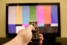 Člověk míří ovladačem na TV.