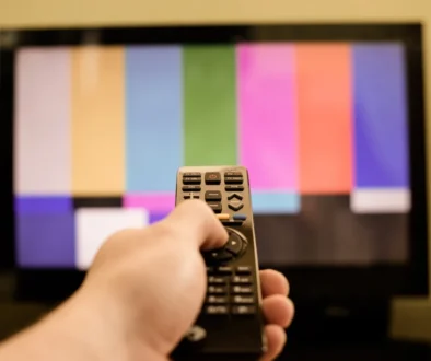 Člověk míří ovladačem na TV.