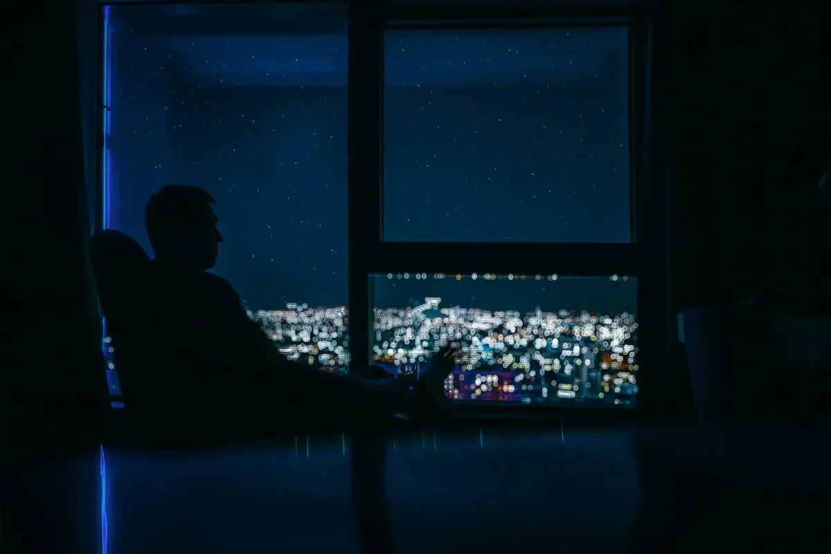 Nevídaný úkaz bylo možné sledovat i ve městech. Zdroj: Shutterstock | TVGURU.cz Člověk dívající se z okna na noční město.