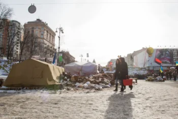 Lidé se prochází po zdevastovaném městě.