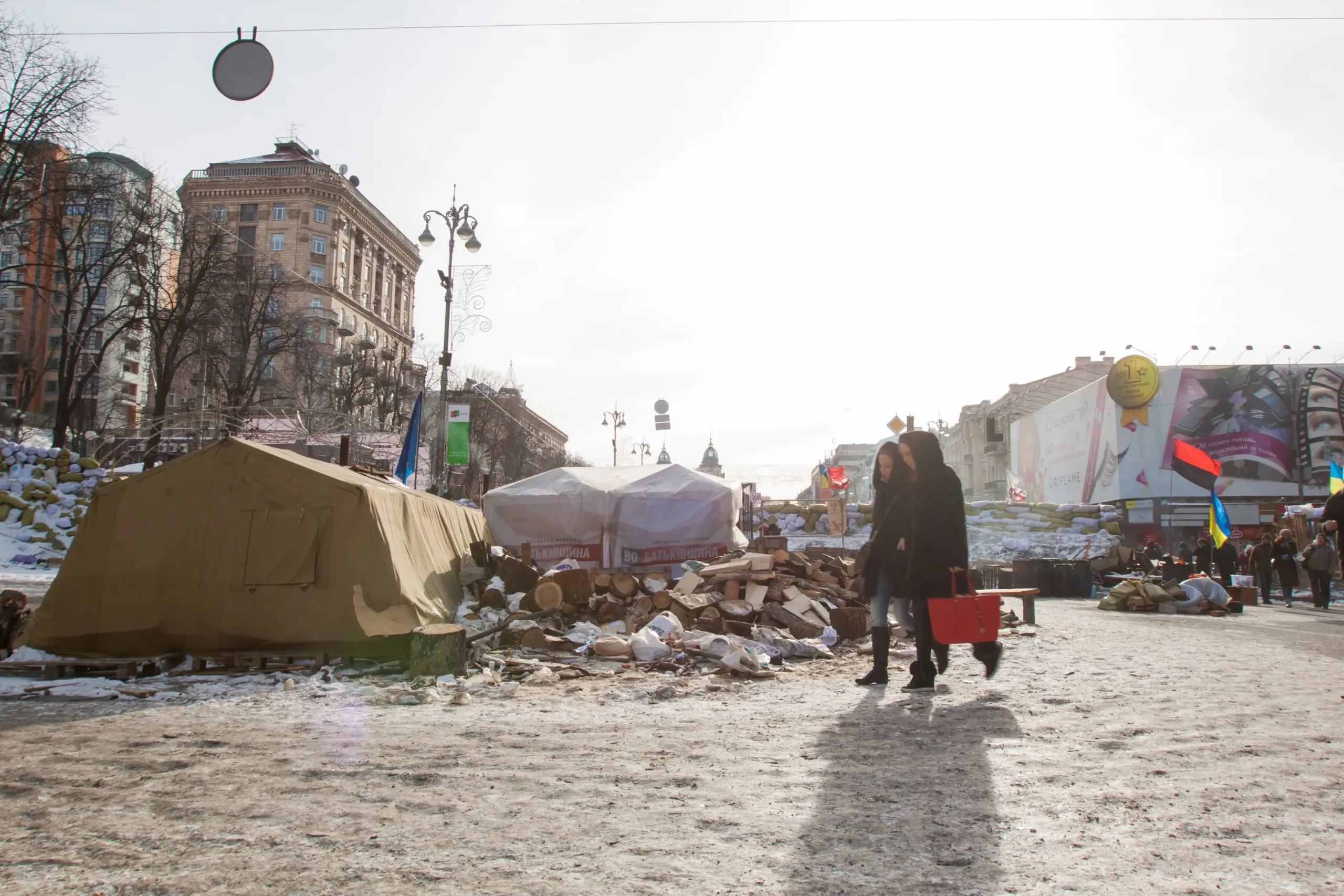 Lidé se prochází po zdevastovaném městě.