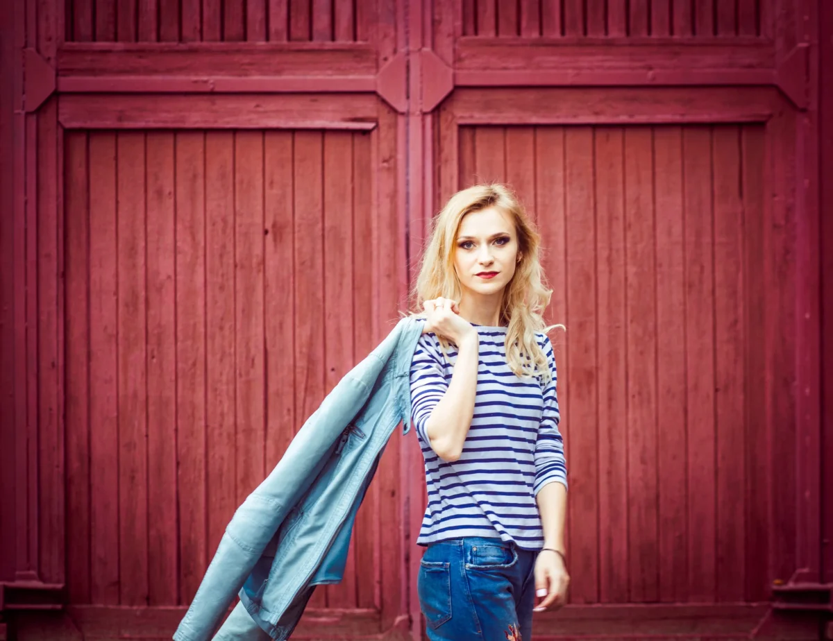 Žena se fotí před červenými vraty.