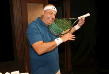 Petr Rychlý má v ruce tenisovou raketu a usmívá se.