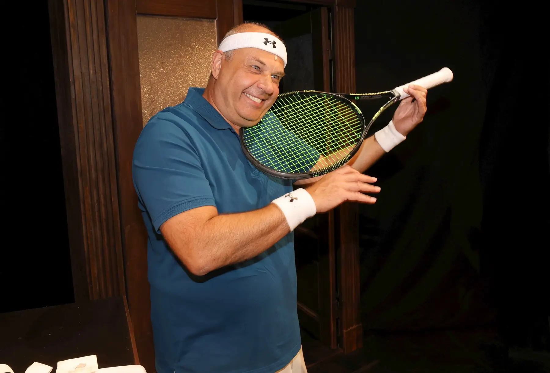 Petr Rychlý má v ruce tenisovou raketu a usmívá se.