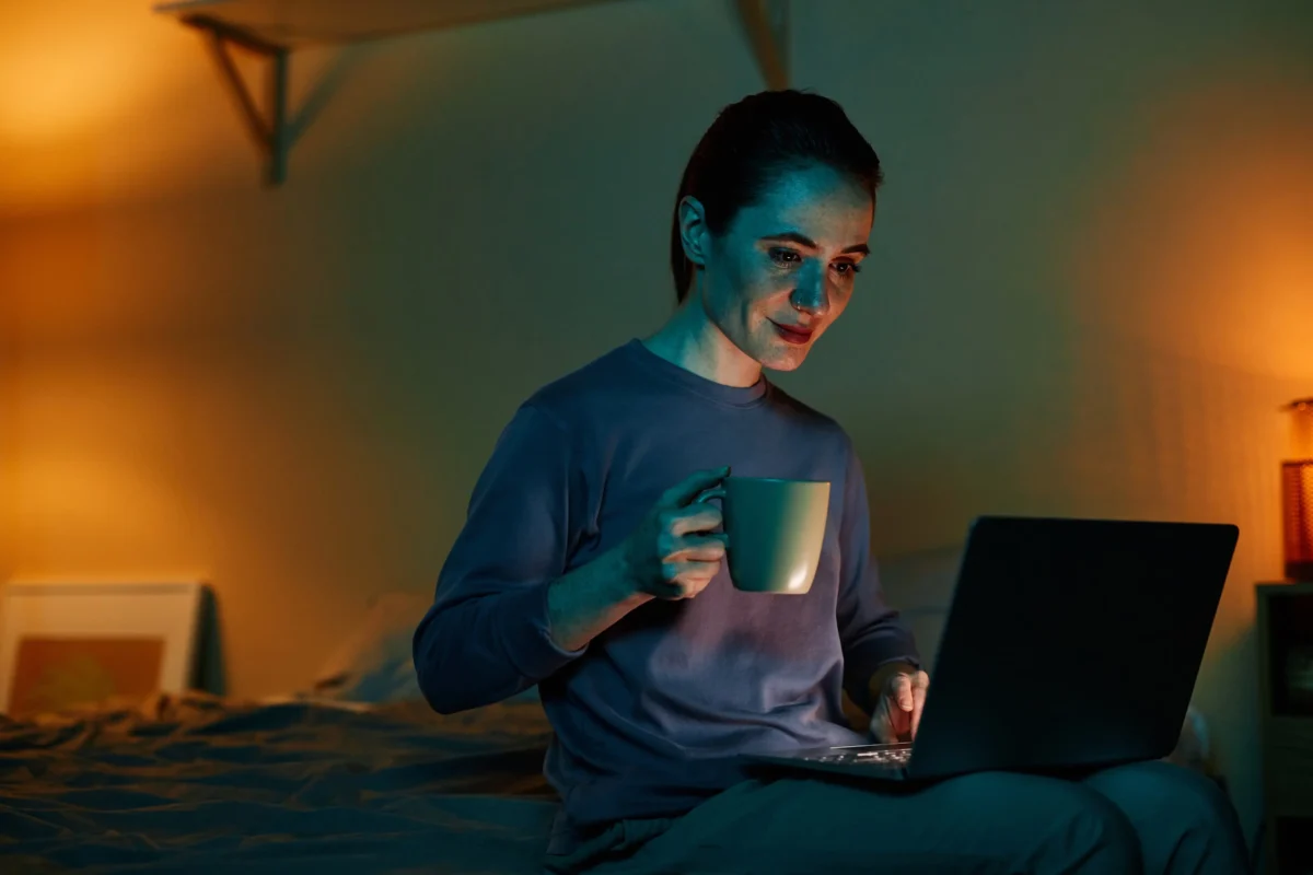 shutterstock_2325788025-2 | TVGURU.cz Žena sedí s notebookem na posteli.