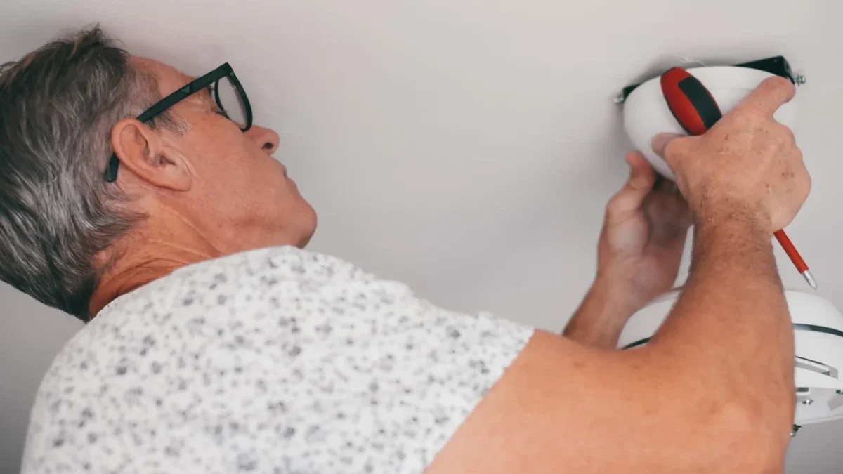 Muž něco šteluje u stropu.