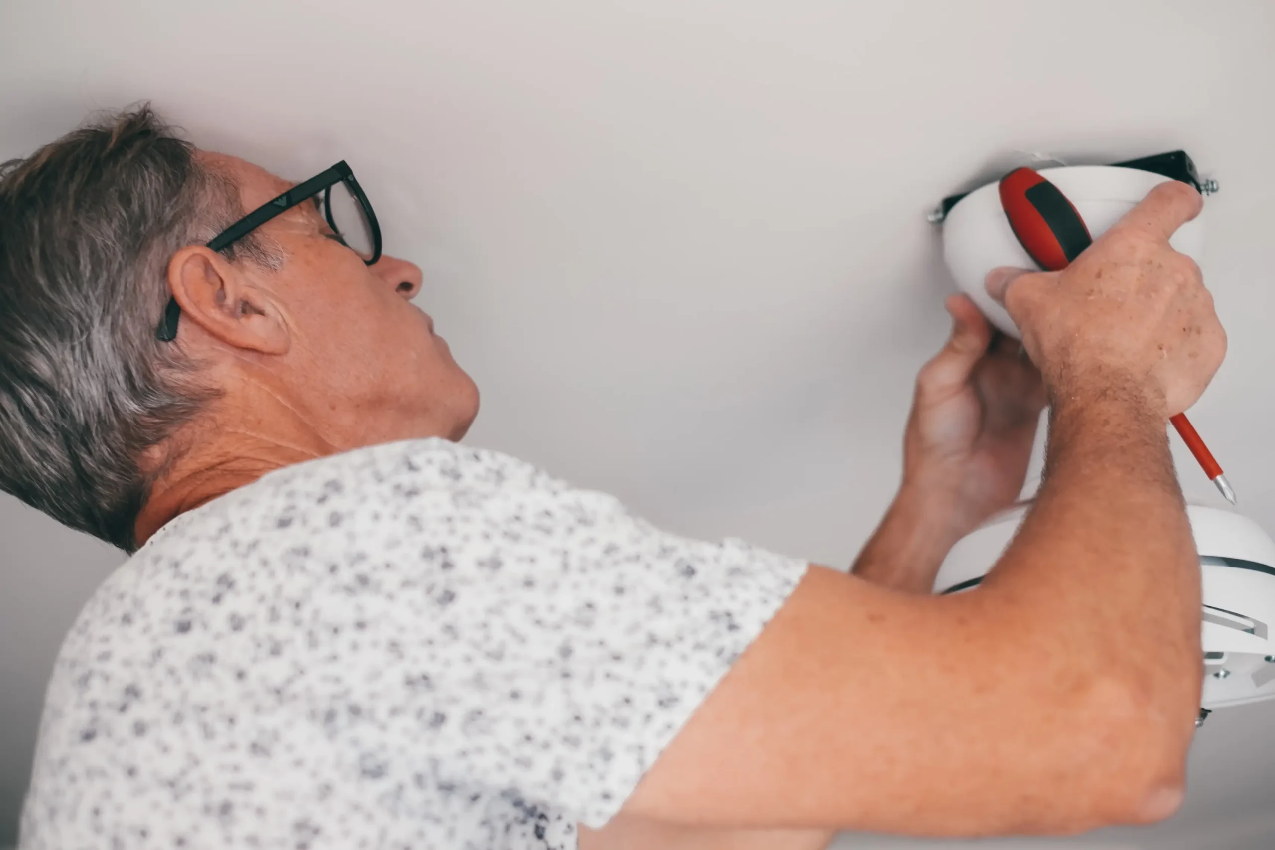 Muž něco šteluje u stropu.