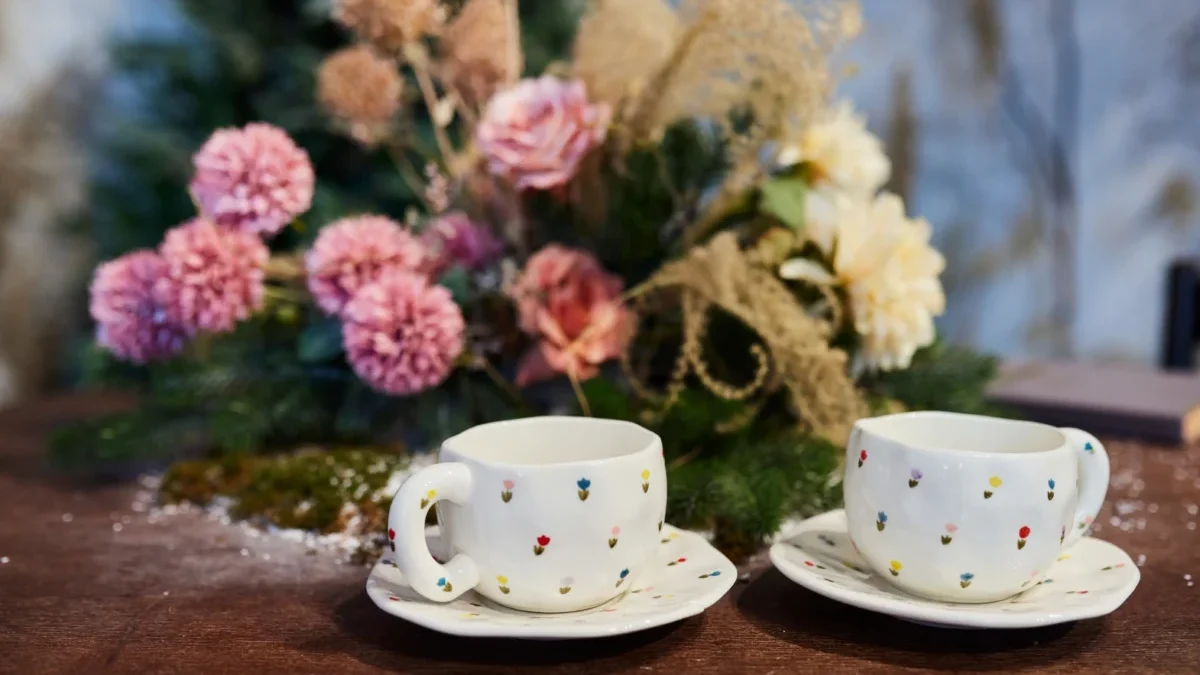 Před květinou stojí dva hrnky.