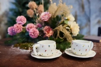 Před květinou stojí dva hrnky.