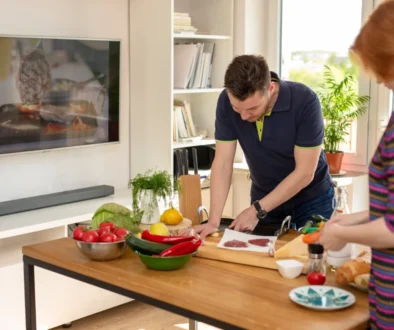 Lidé připravující jídlo v kuchyni u televize.