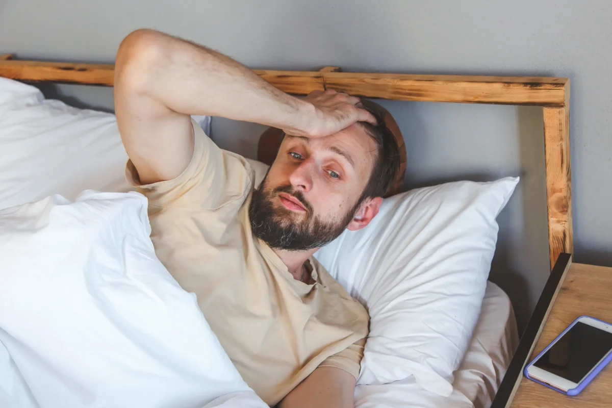 Muž leží nešťastný v posteli.