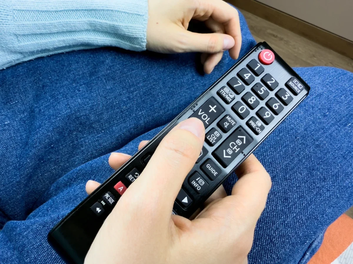 Člověk v ruce drží ovladač od TV.
