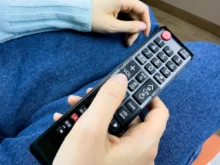 Člověk v ruce drží ovladač od TV.