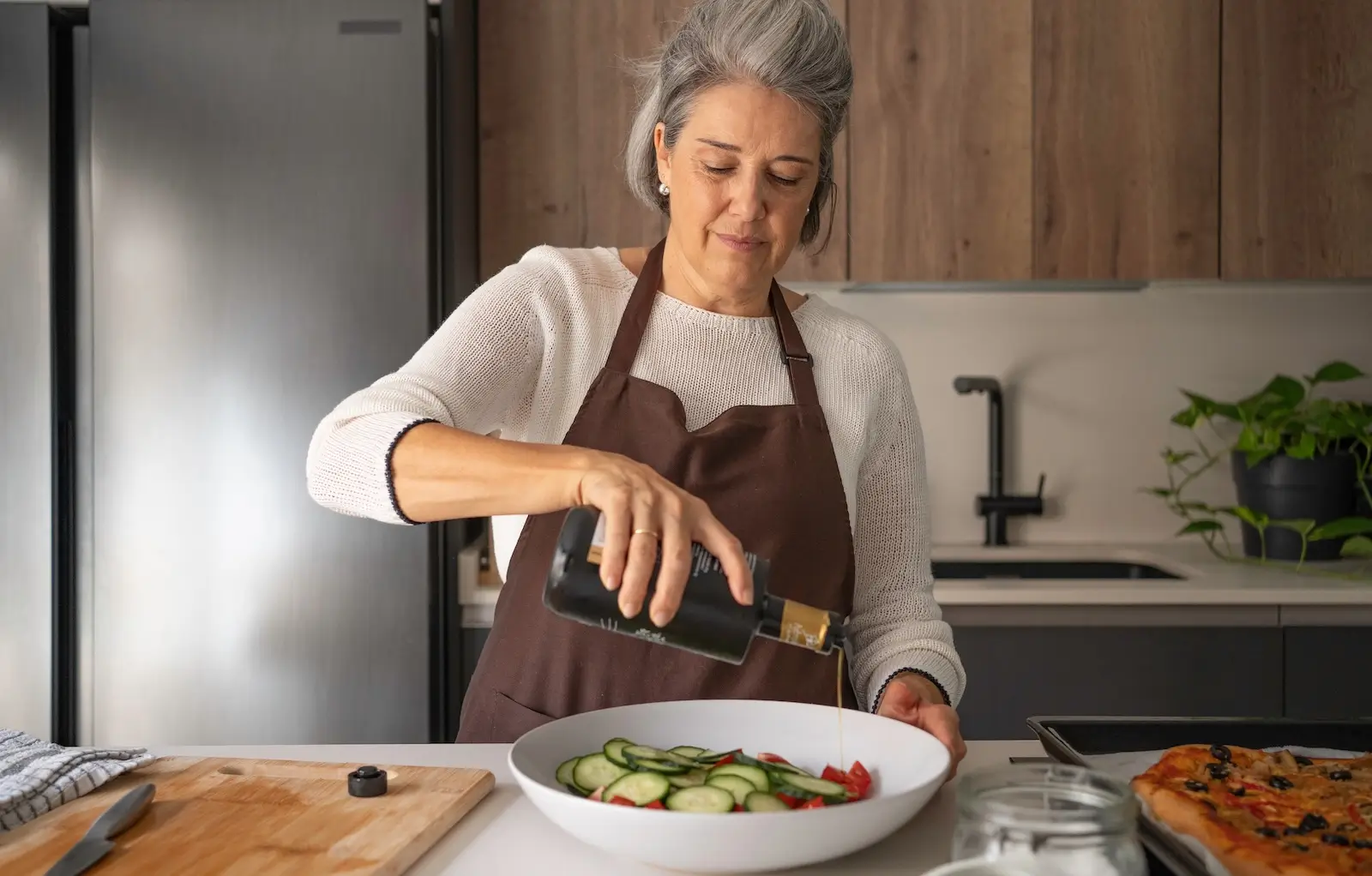 žena nalévá olej do salátu