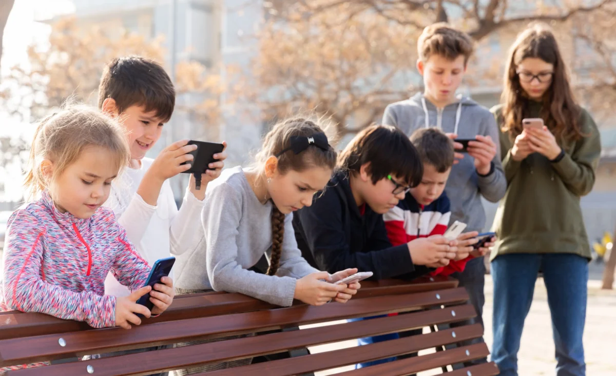 Děti hrající si na telefonu. 