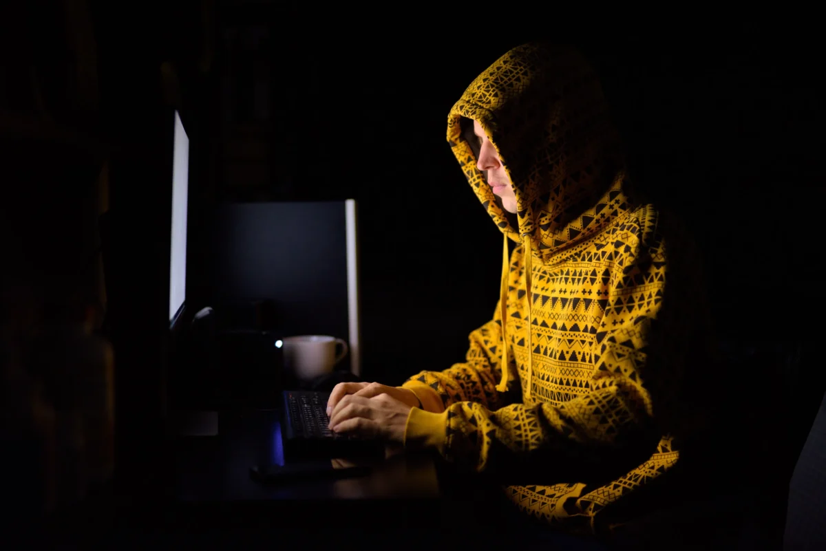 Muž sedí ve tmě u počítače.