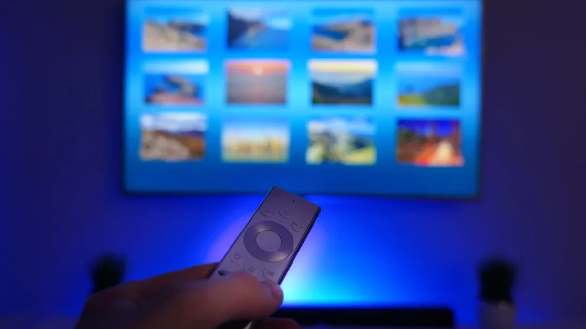 Člověk ovladačem míří na obrazovku TV.