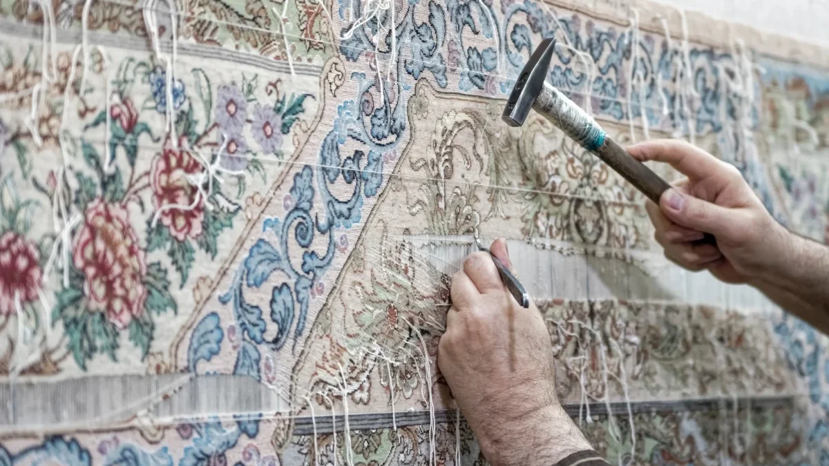 Člověk opravuje perský koberec.