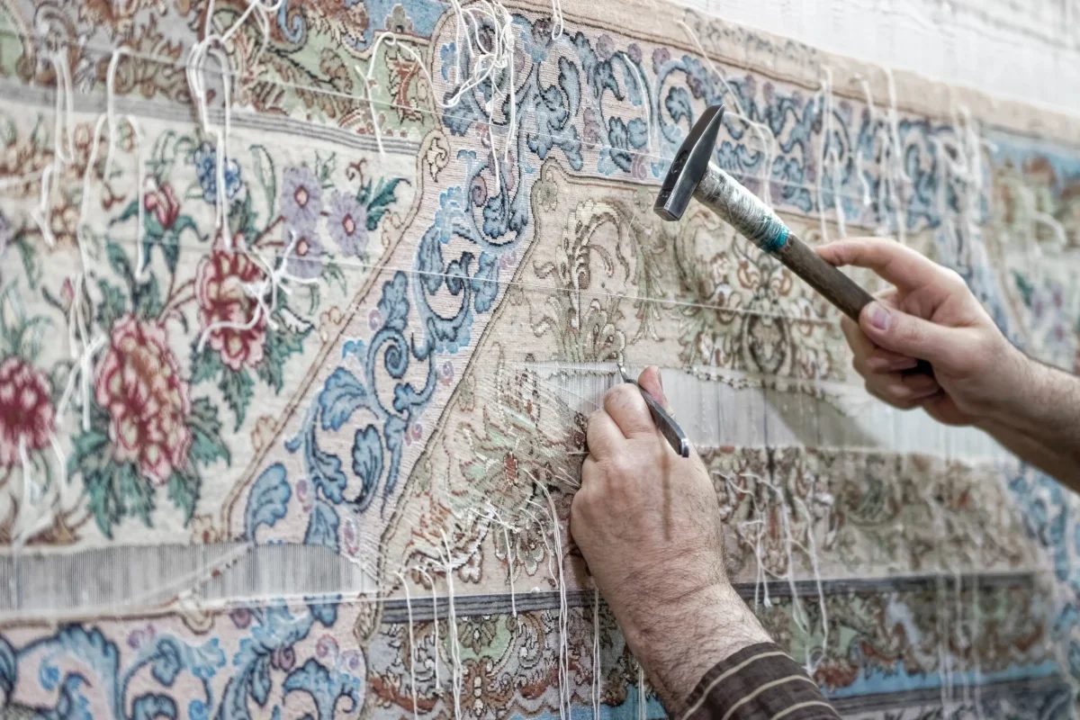 Člověk opravuje perský koberec.