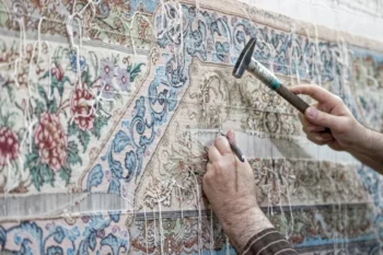 Člověk opravuje perský koberec.