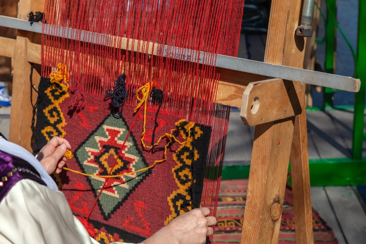 Žena šije perský koberec.