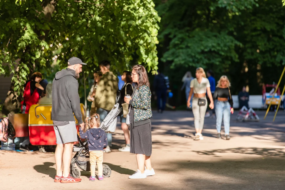 shutterstock_2233209957-2 | TVGURU.cz Rodina stojí v parku mezi ostatními lidmi.