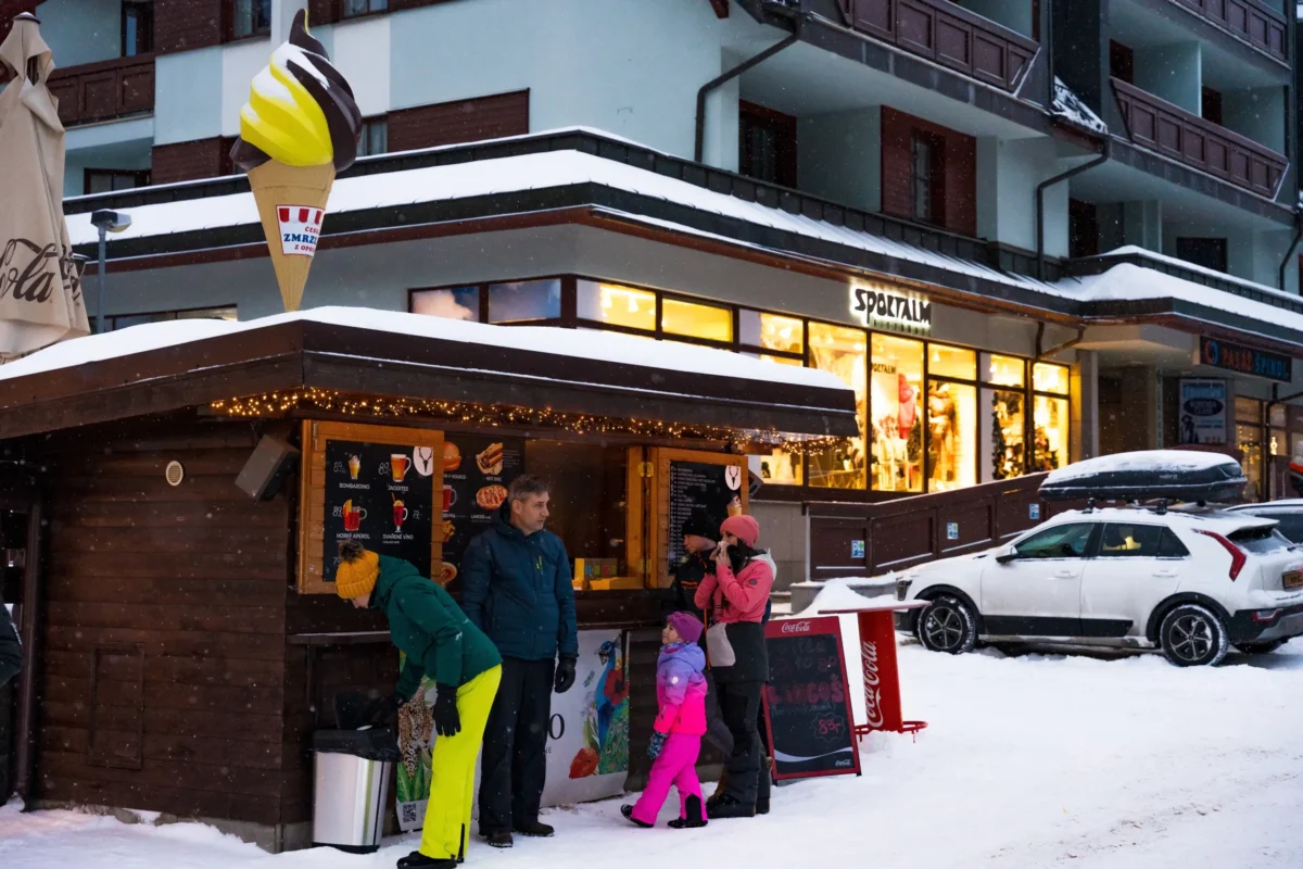 shutterstock_2580868423-2-2 | TVGURU.cz Lidé jsou u stánku pod sjezdovkou.