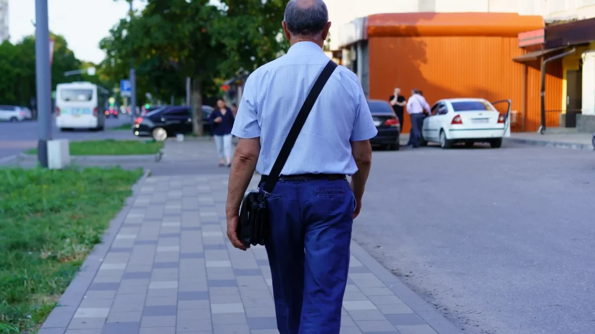 Starší muž se prochází po chodníku.