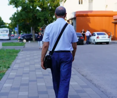 Starší muž se prochází po chodníku.