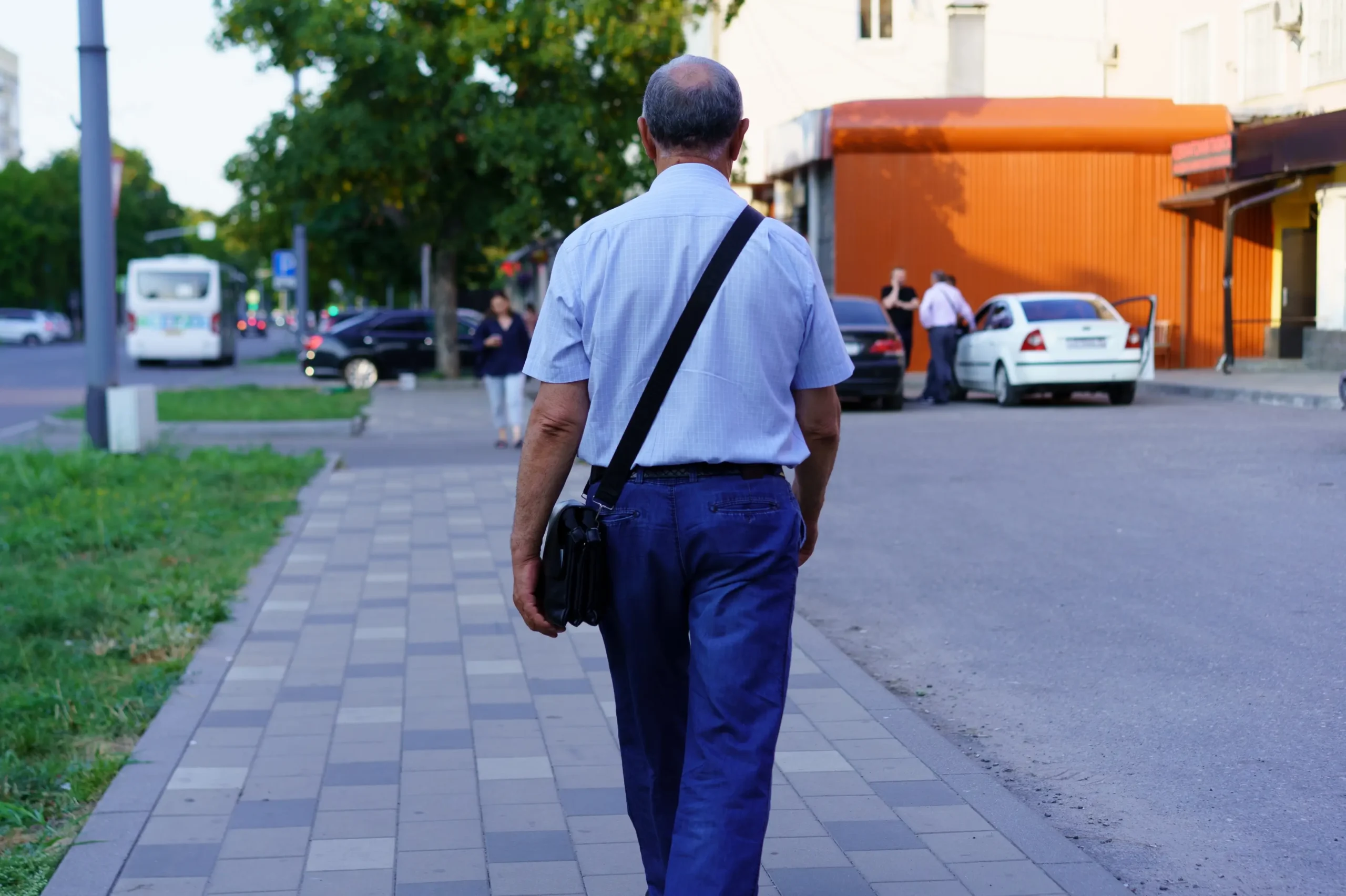 Starší muž se prochází po chodníku.