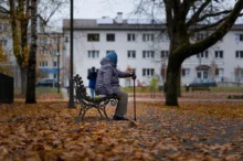 Babička sedí venku na lavičce.