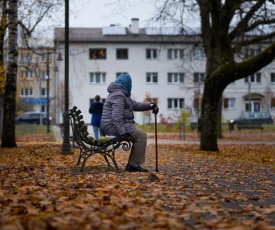 Babička sedí venku na lavičce.
