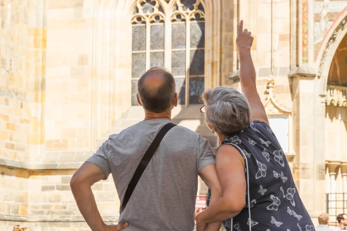 Starší pár ukazuje na budovu před sebou.