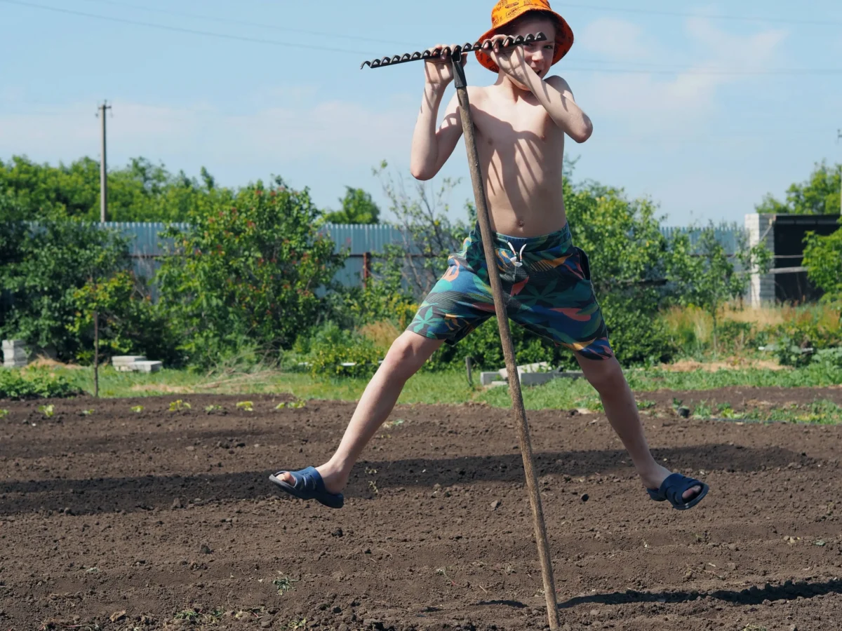 Chlapec skáče s vidlemi po poli. 