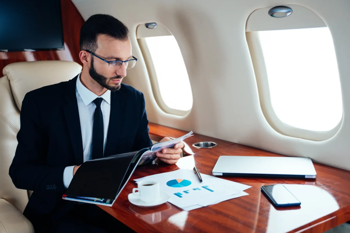 Muž letí v soukromém letadle a čte něco z papírů. 