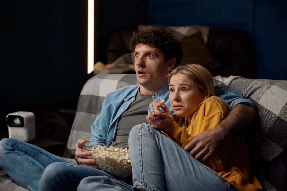 Mladý pár na gauči sleduje tv