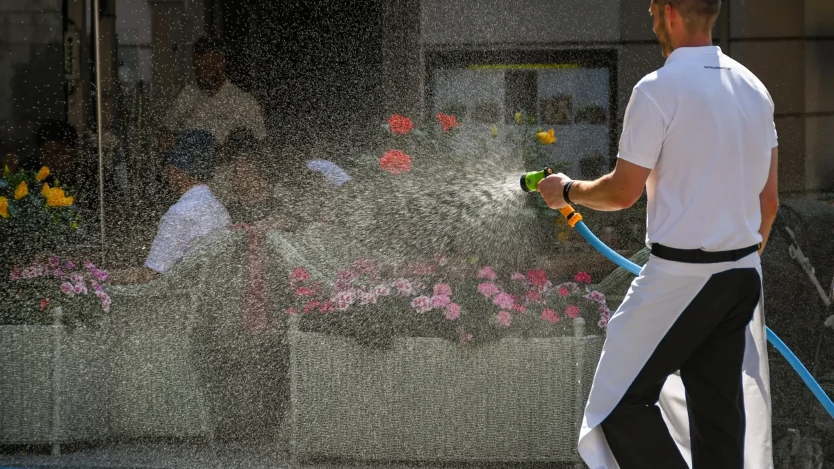 Muž kropí květiny.