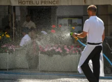 Muž kropí květiny.