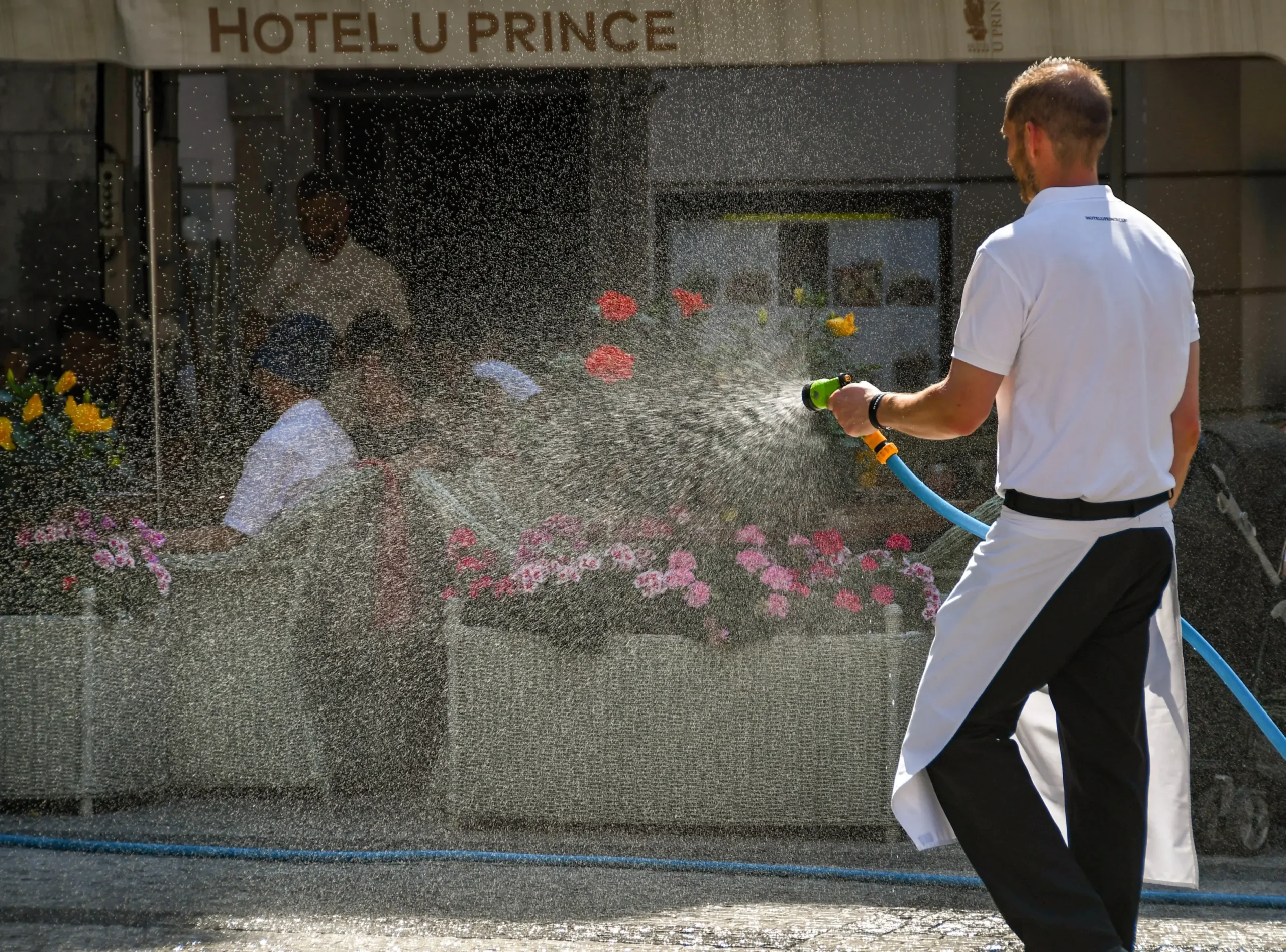 Muž kropí květiny.