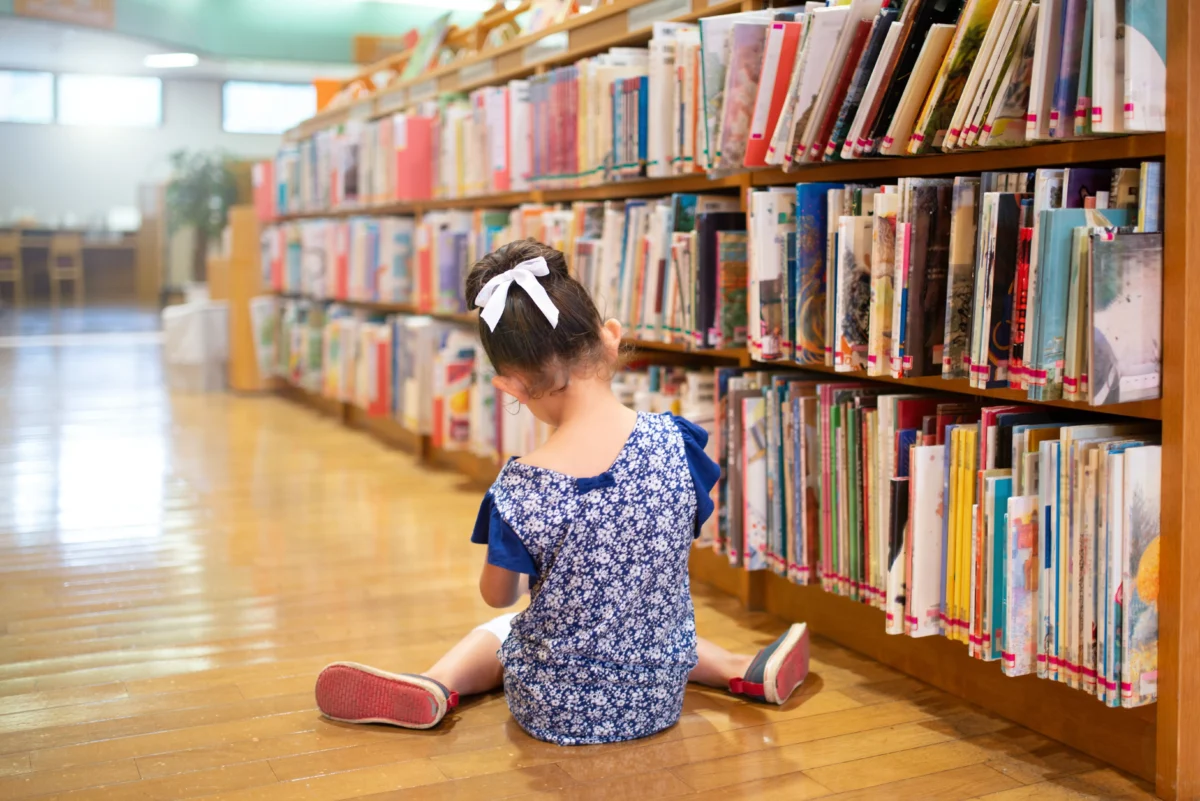 Dítě sedí v knihovně.