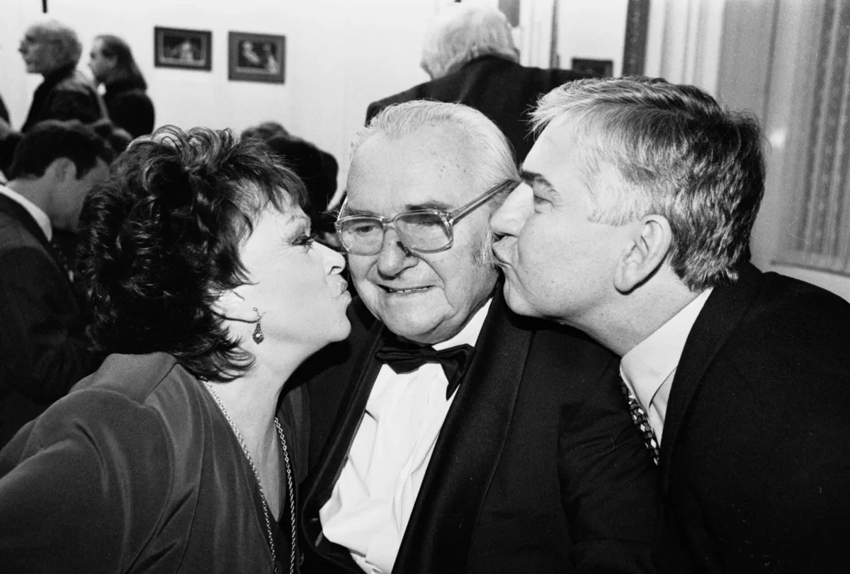 Jiří Sovák dostává pusu na tvář od hereckých kolegů. 