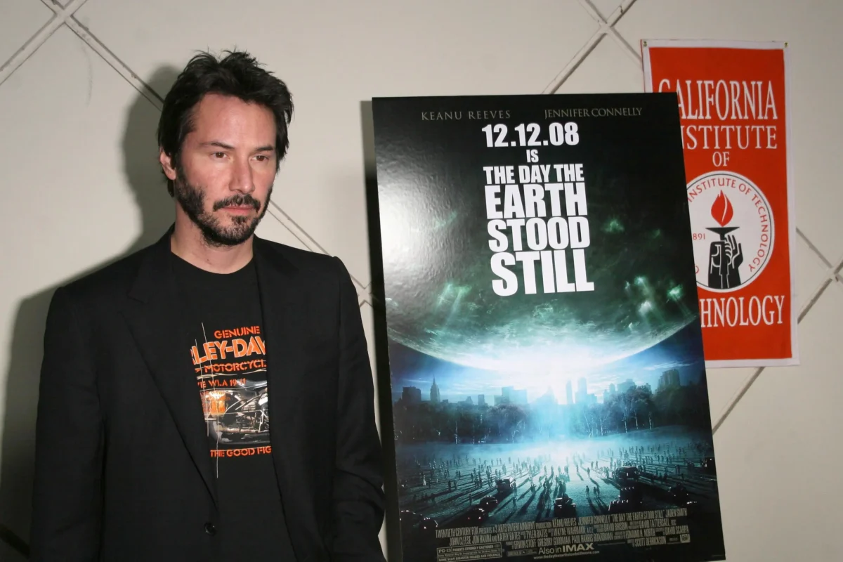 Keanu Reeves stojí vedle plakátu. 