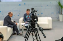 Natáčení dvou mužů, kteří sedí na gauči.