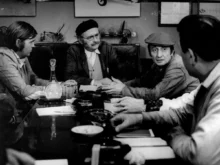 Muži sedí u stolu.