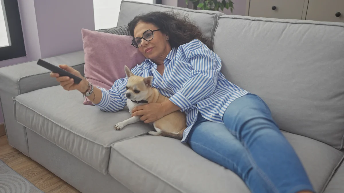 Žena s čivavou leží na gauči. 