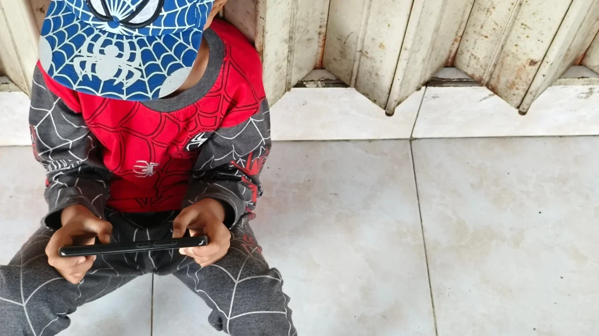 Chlapeček v oblečení Spider-Mana sedí na zemi.