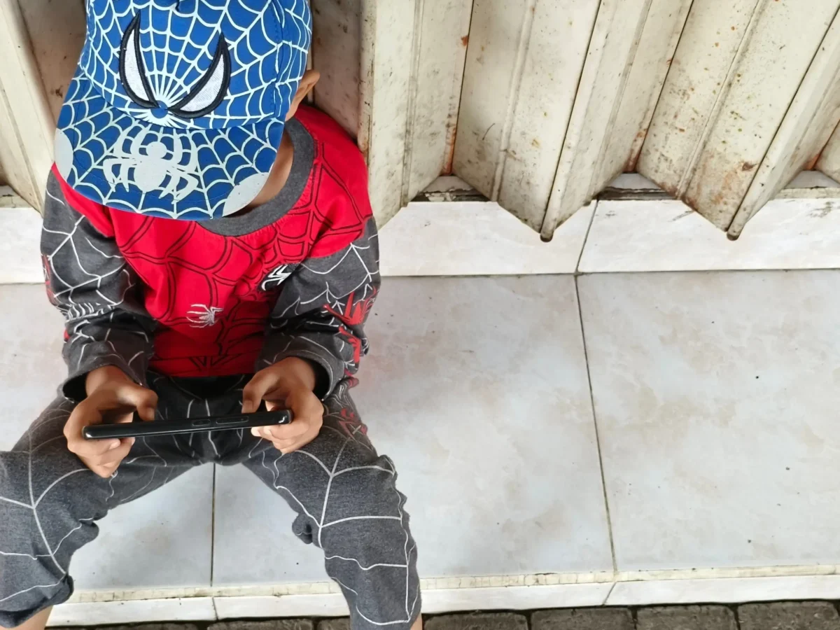 Chlapeček v oblečení Spider-Mana sedí na zemi.